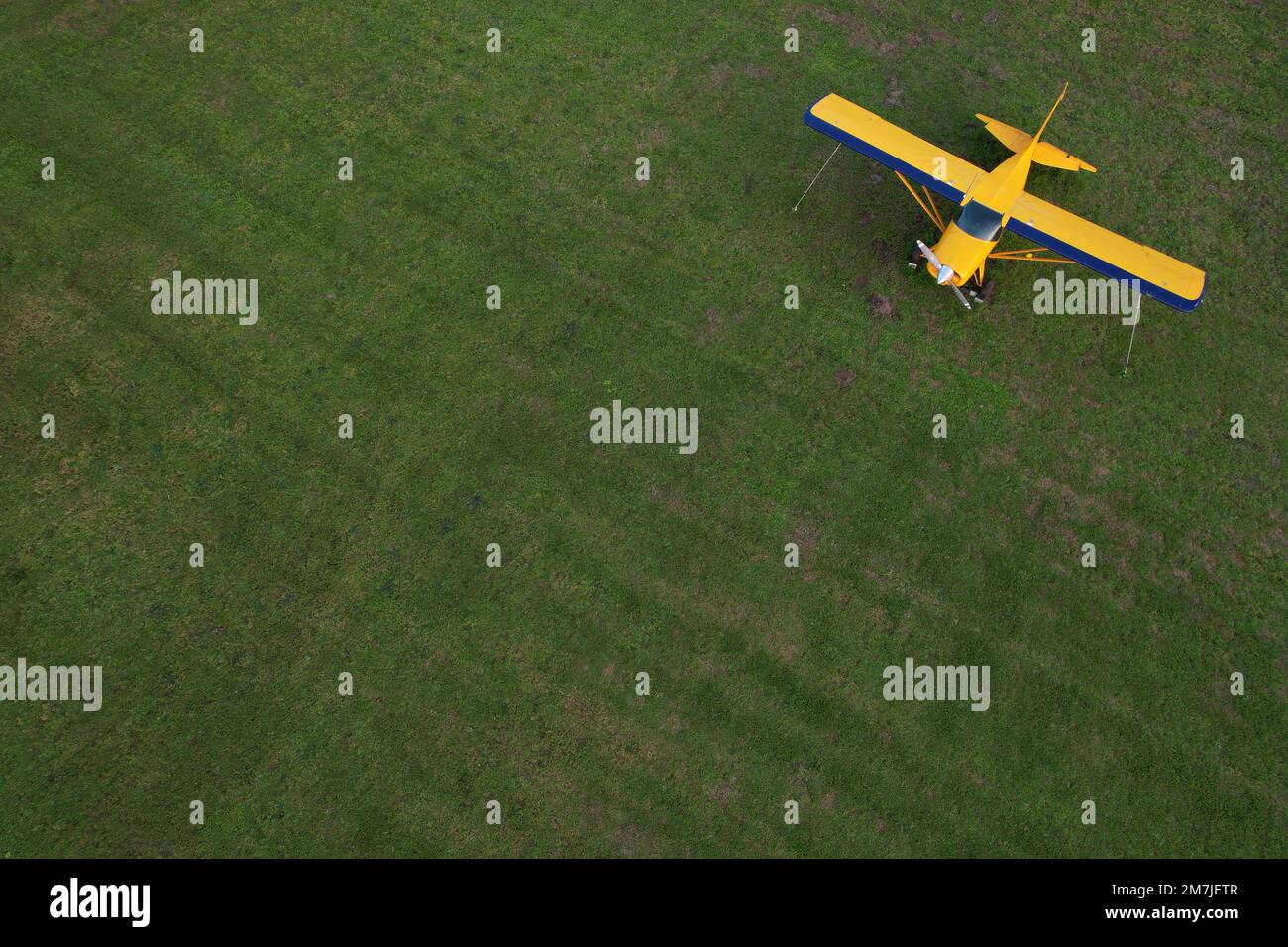 piccolo aereo giallo utilizzato per brevi viaggi visti dall'alto parcheggiato su un campo verde Foto Stock