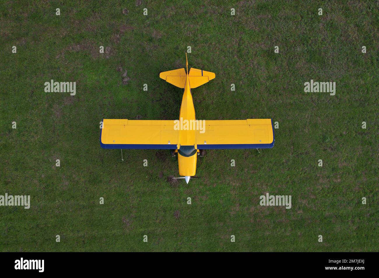 piccolo aereo giallo utilizzato per brevi viaggi visti dall'alto parcheggiato su un campo verde Foto Stock