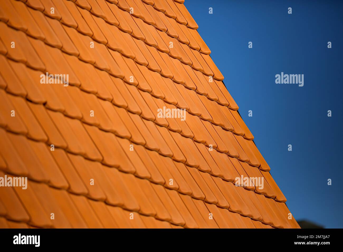Dettagli dei motivi del tetto in mattoni arancioni con un cielo blu chiaro sullo sfondo. Primo piano dei modelli di architettura delle case. Foto Stock