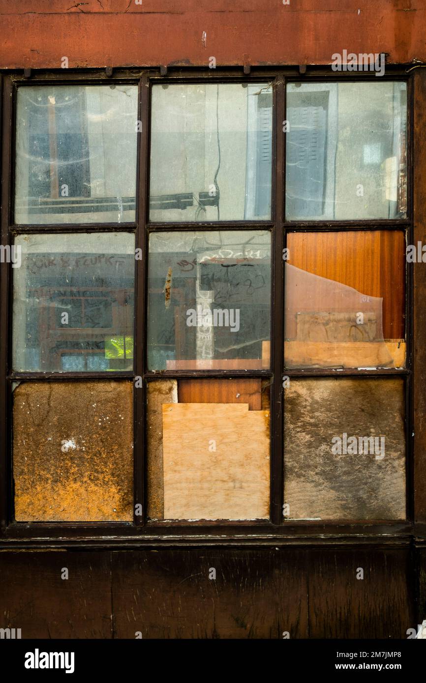 Immagine verticale di una vecchia finestra retrò nella facciata coperta di vecchie carte Foto Stock