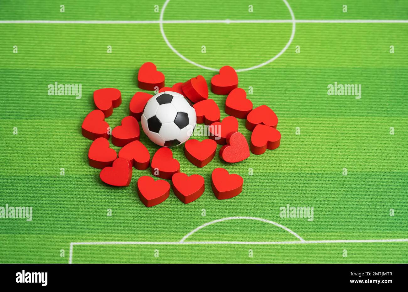 Pallone da calcio e cuori rossi su sfondo verde erba Foto Stock