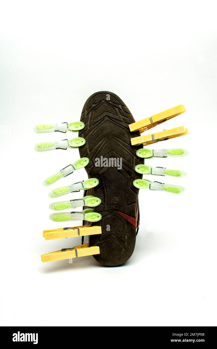 Foto verticale di clothespins ritagliati su una sneaker isolata sullo sfondo bianco vuoto Foto Stock