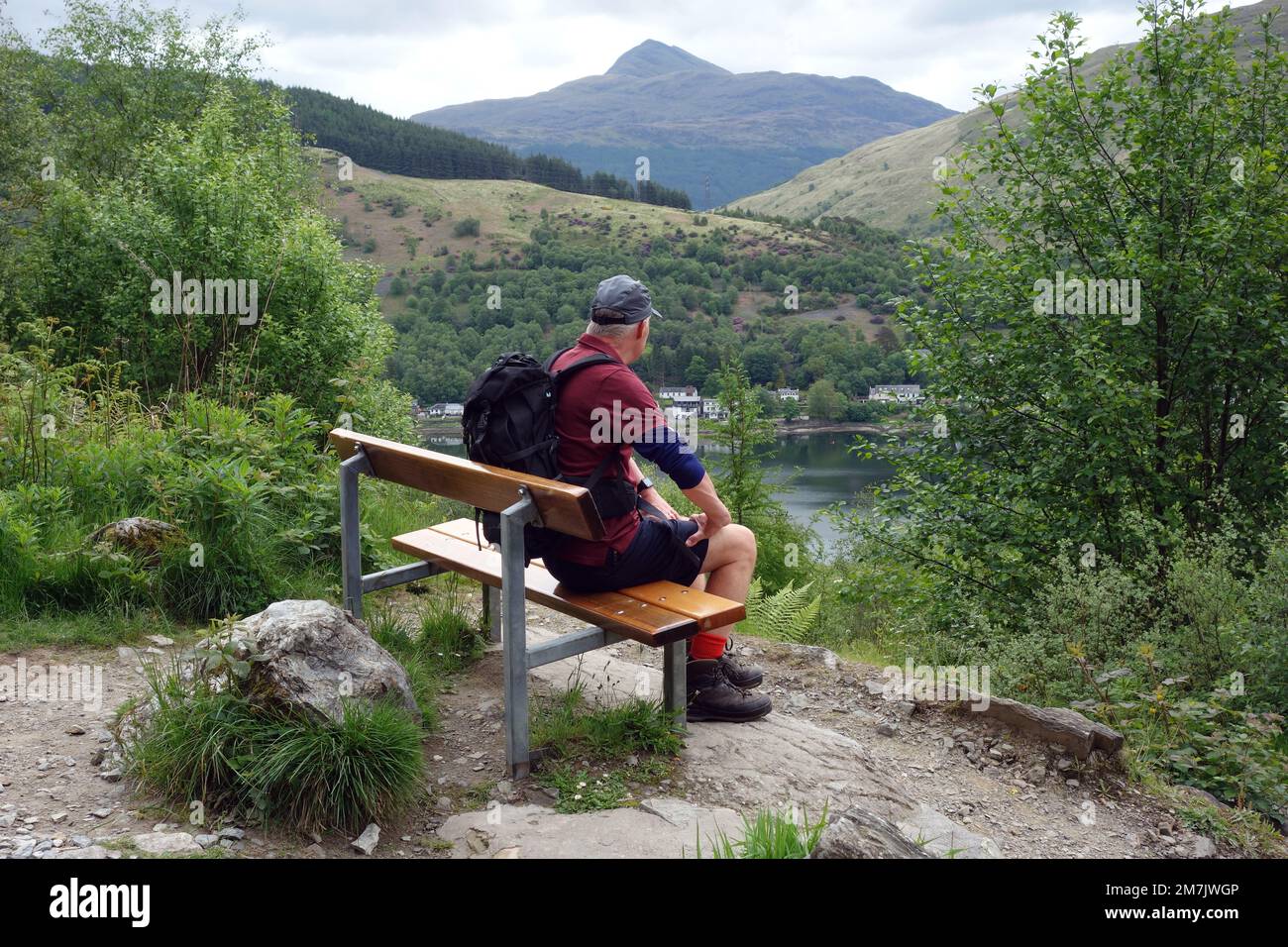 Old Man Sab on Bench sopra Loch Long vicino ad Arrochar guardando la montagna scozzese Munro 'ben Lomond' nelle Highlands scozzesi, Scozia. Foto Stock