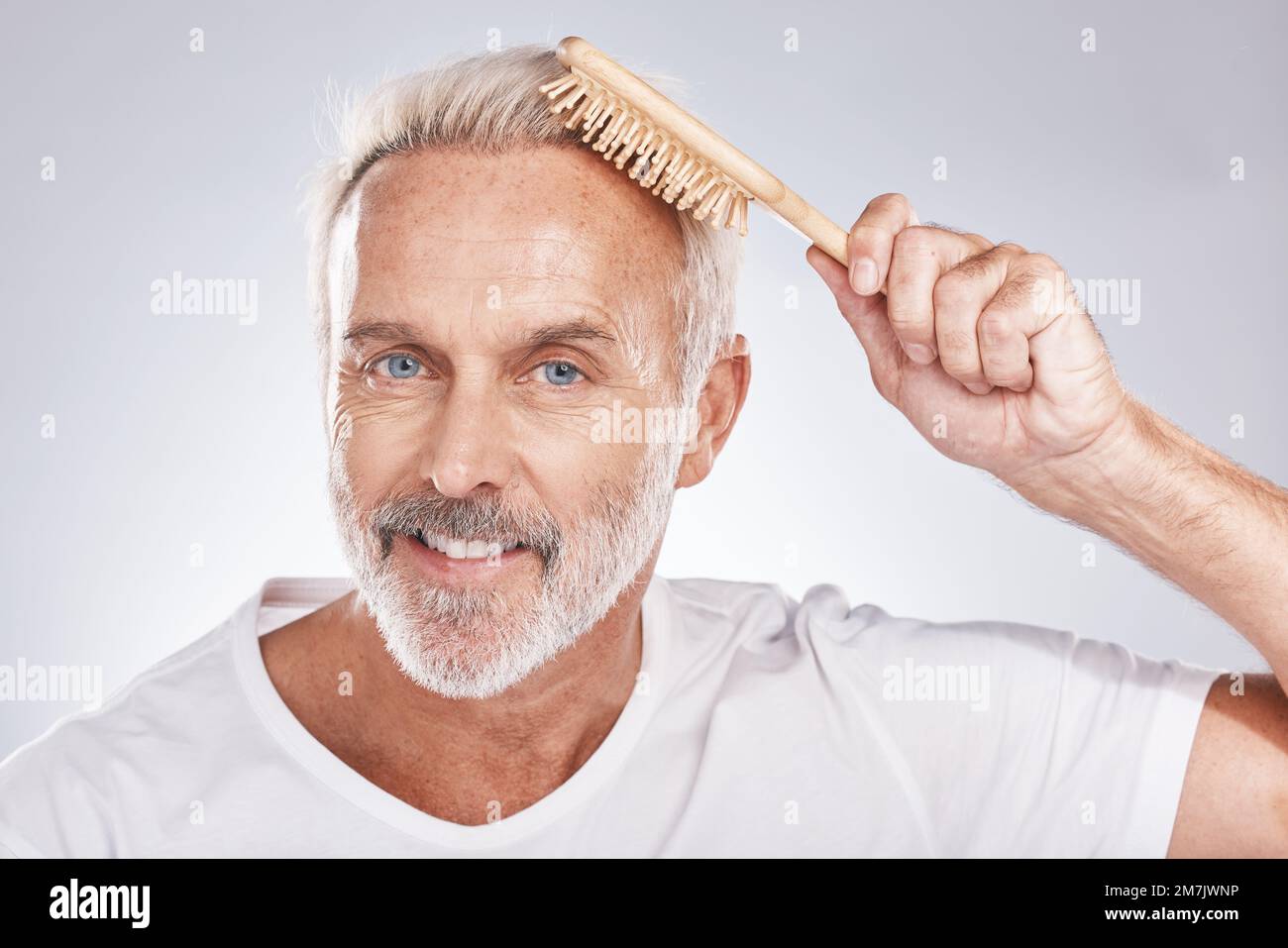 Ritratto uomo spazzola capelli su sfondo studio per la bellezza, salone di barbiere e cosmetici. Viso felice, modello maschile e pettine per la cura di sé di liscio Foto Stock