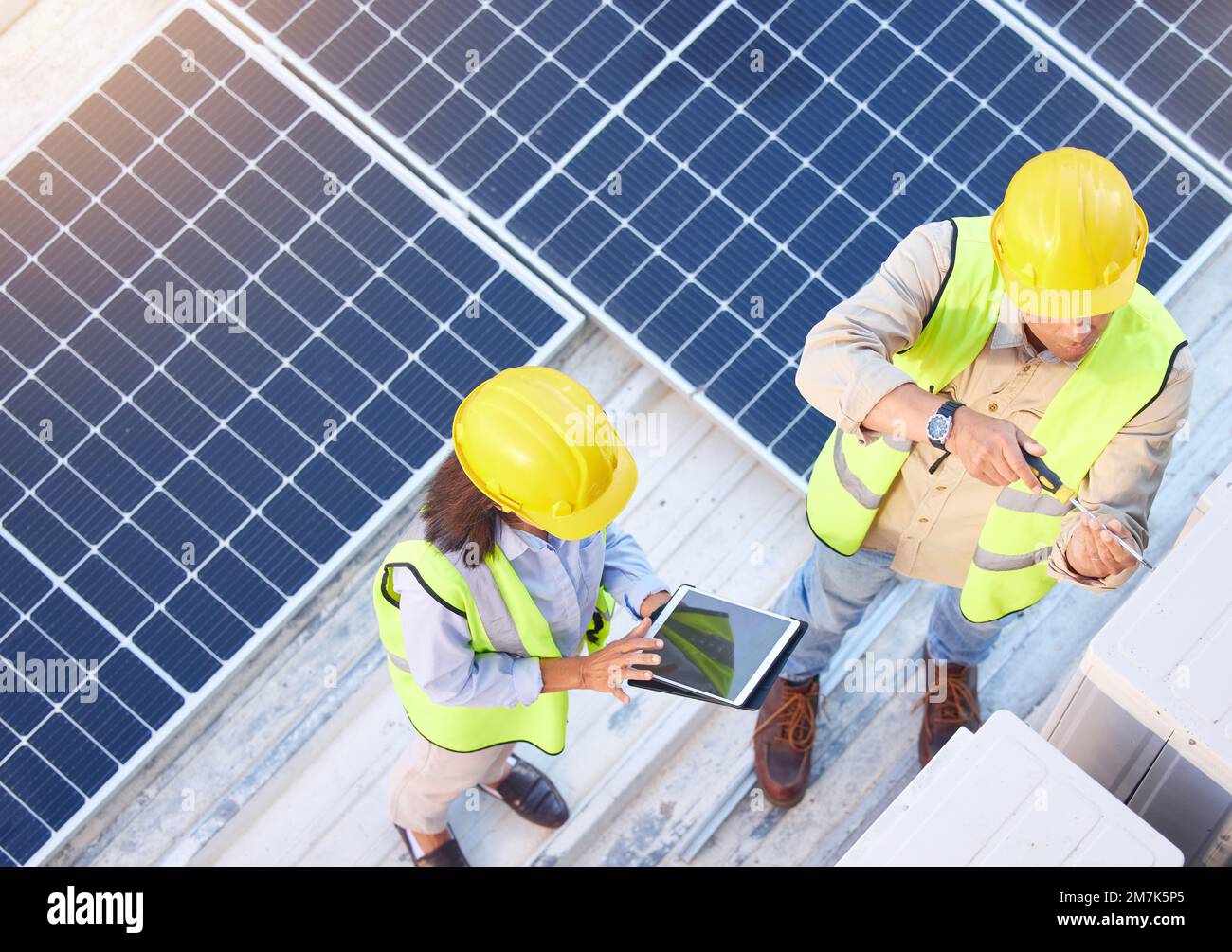 Vista dall'alto, lavoro di squadra e ingegneri con tablet sul tetto solare per manutenzione, ispezione o installazione. Energia solare, energia rinnovabile e uomo e. Foto Stock