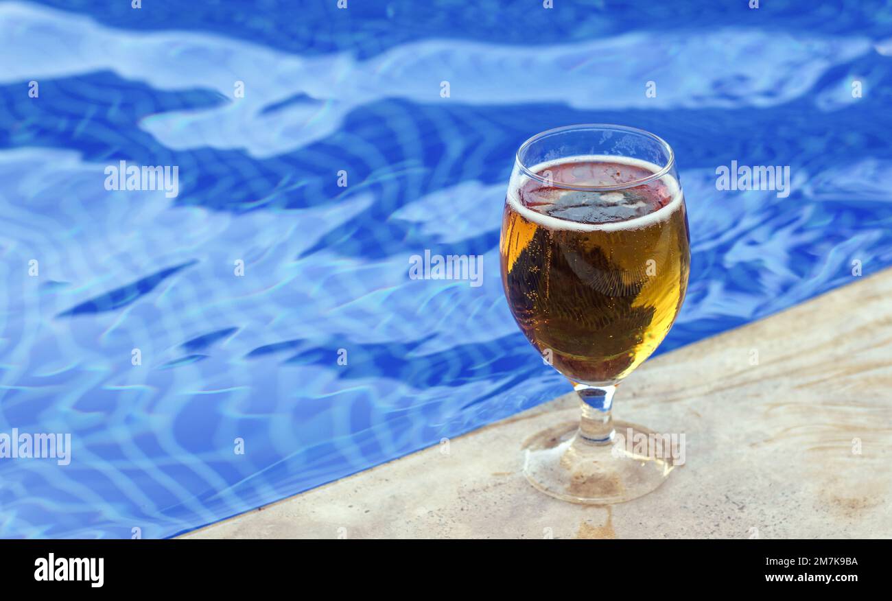 bicchiere con birra fresca fredda sul bordo piscina blu acqua di colore onde mockup spazio libero per copia di testo paste. vacanza tempo umore viaggio tutto compreso hotel tri Foto Stock