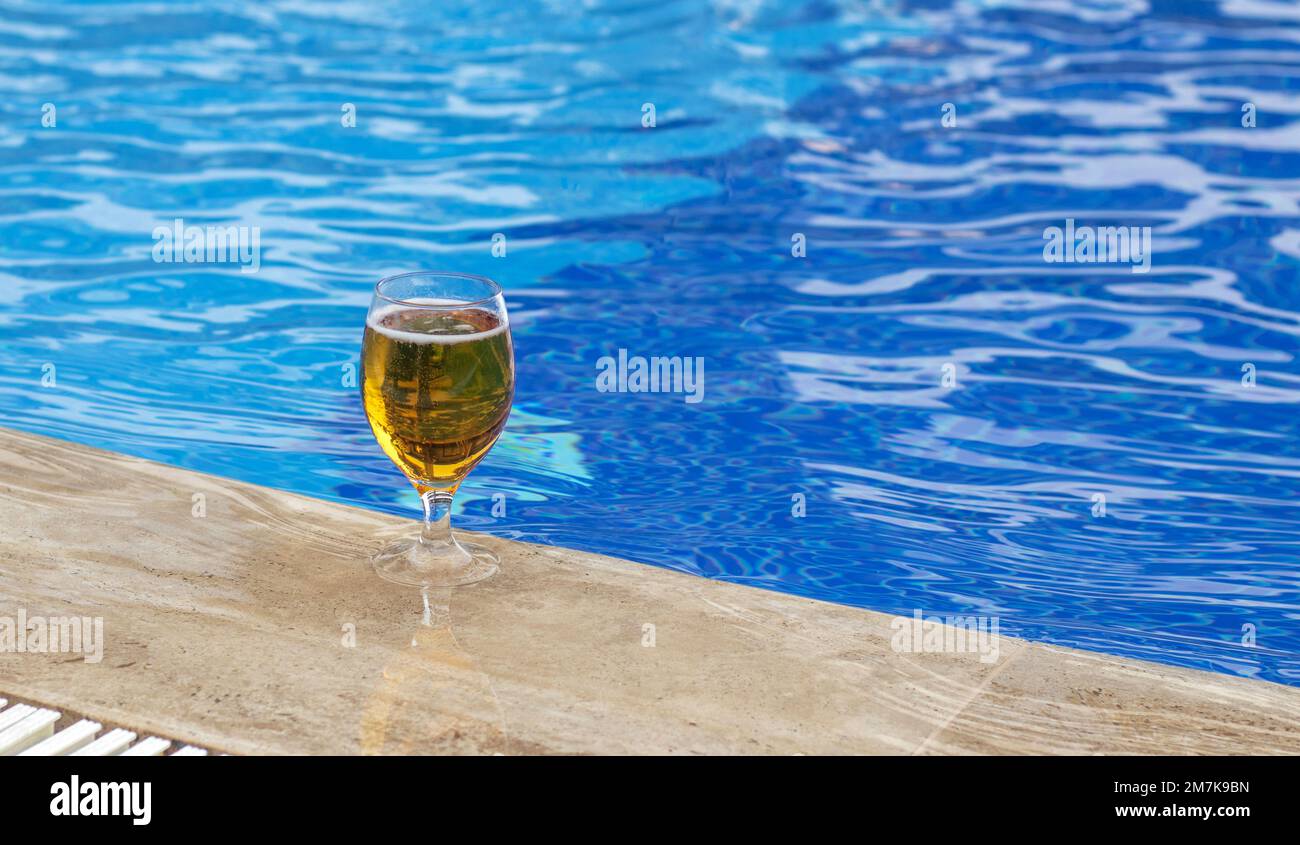 bicchiere con birra fresca fredda sul bordo piscina blu acqua di colore onde mockup spazio libero per copia di testo paste. vacanza tempo umore viaggio tutto compreso hotel tri Foto Stock