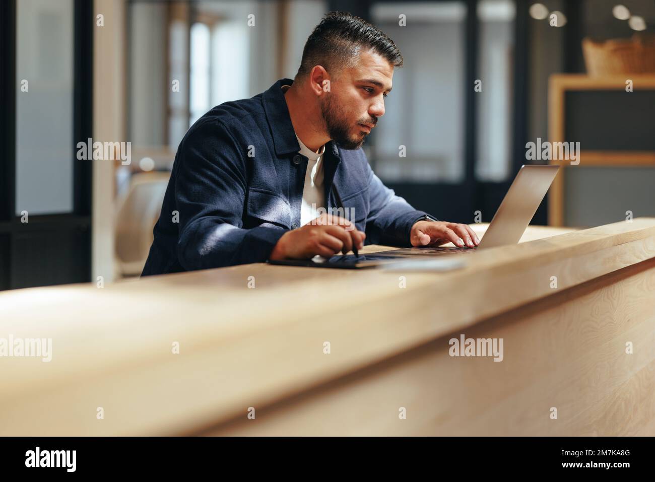 Web design professionale che lavora su un computer portatile in un ufficio di coworking. Uomo d'affari creativo che disegnano su un tablet grafico. Designer maschile che fa lavoro a distanza Foto Stock