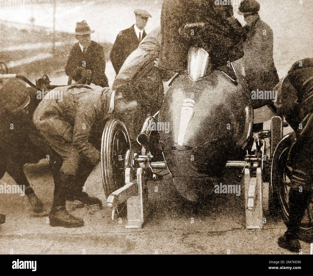 Un'immagine 1930 di secondi (meccanici) che cambiano gli pneumatici in un pit stop in un circuito automobilistico britannico Foto Stock