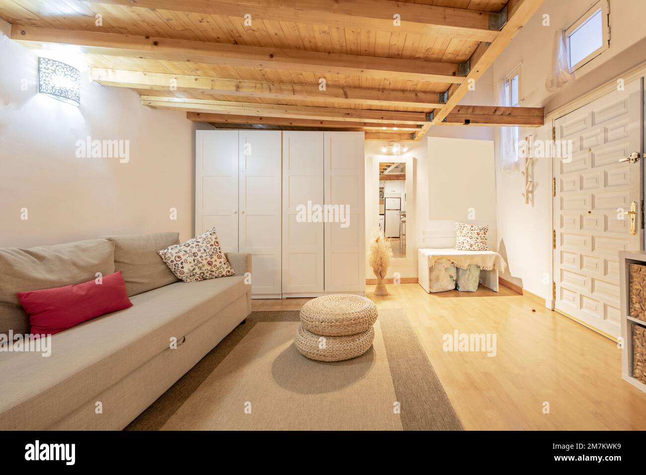 Appartamento mansardato in legno di pino con mobili bianchi al piano terra, con porta d'accesso rivestita in pannelli e pavimenti in parquet con tappeto beige Foto Stock