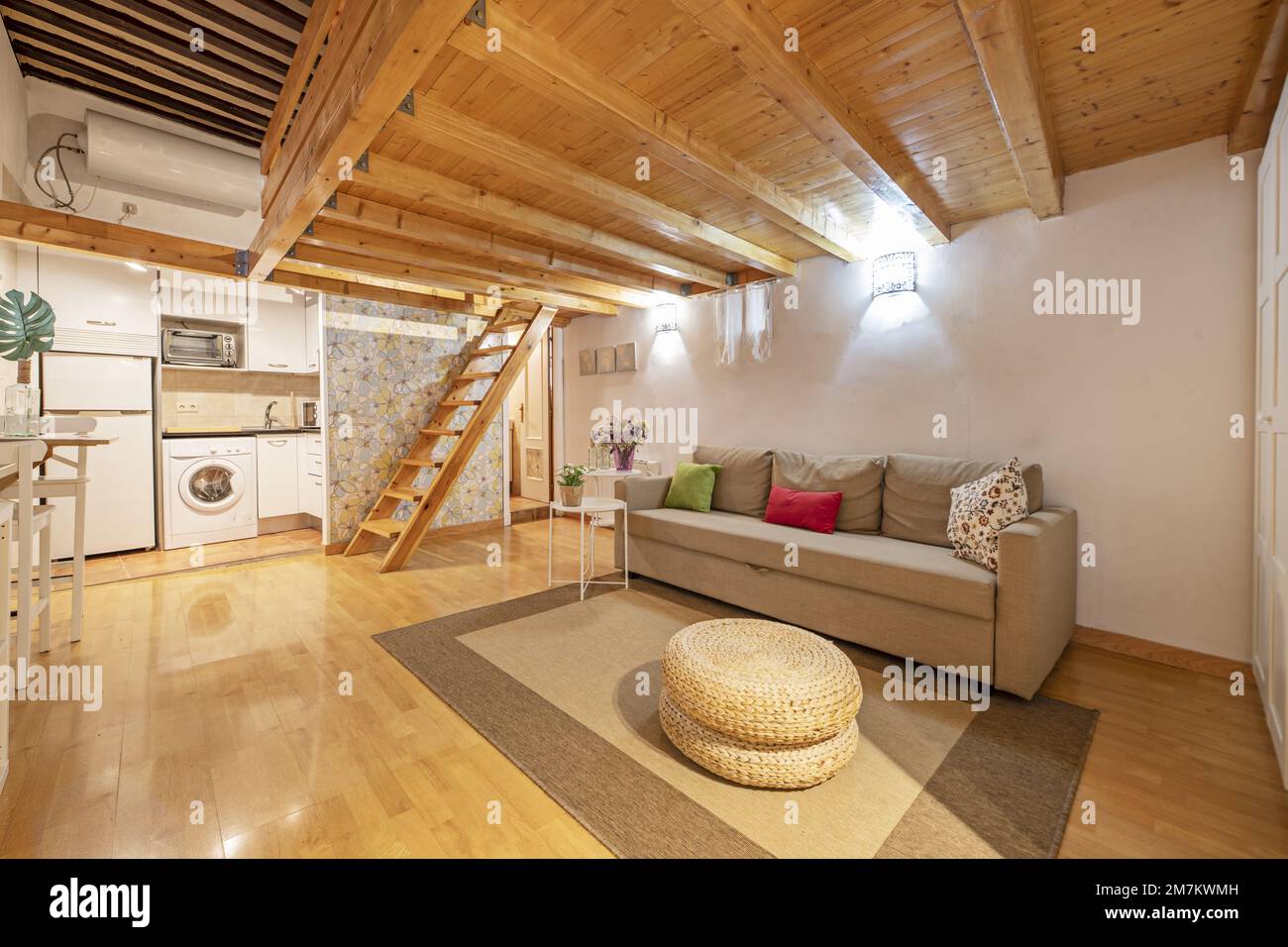 Appartamento loft con pannelli in legno di pino e mobili bianchi al piano terra, scala in legno coordinata e pavimenti in parquet con tappeto beige e A. Foto Stock