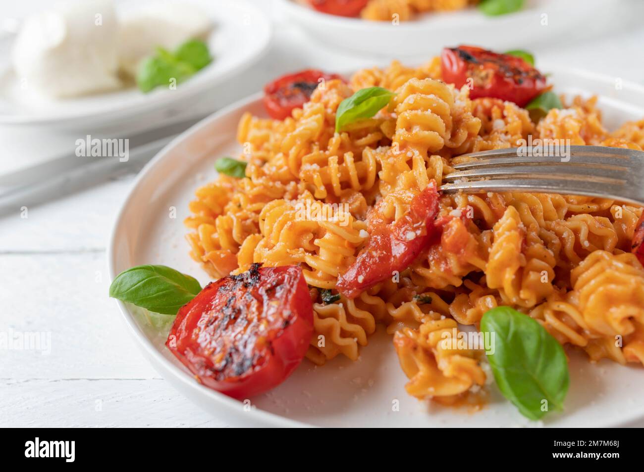 Pasta con salsa di mozzarella di pomodoro, parmigiano e basilico su un piatto Foto Stock