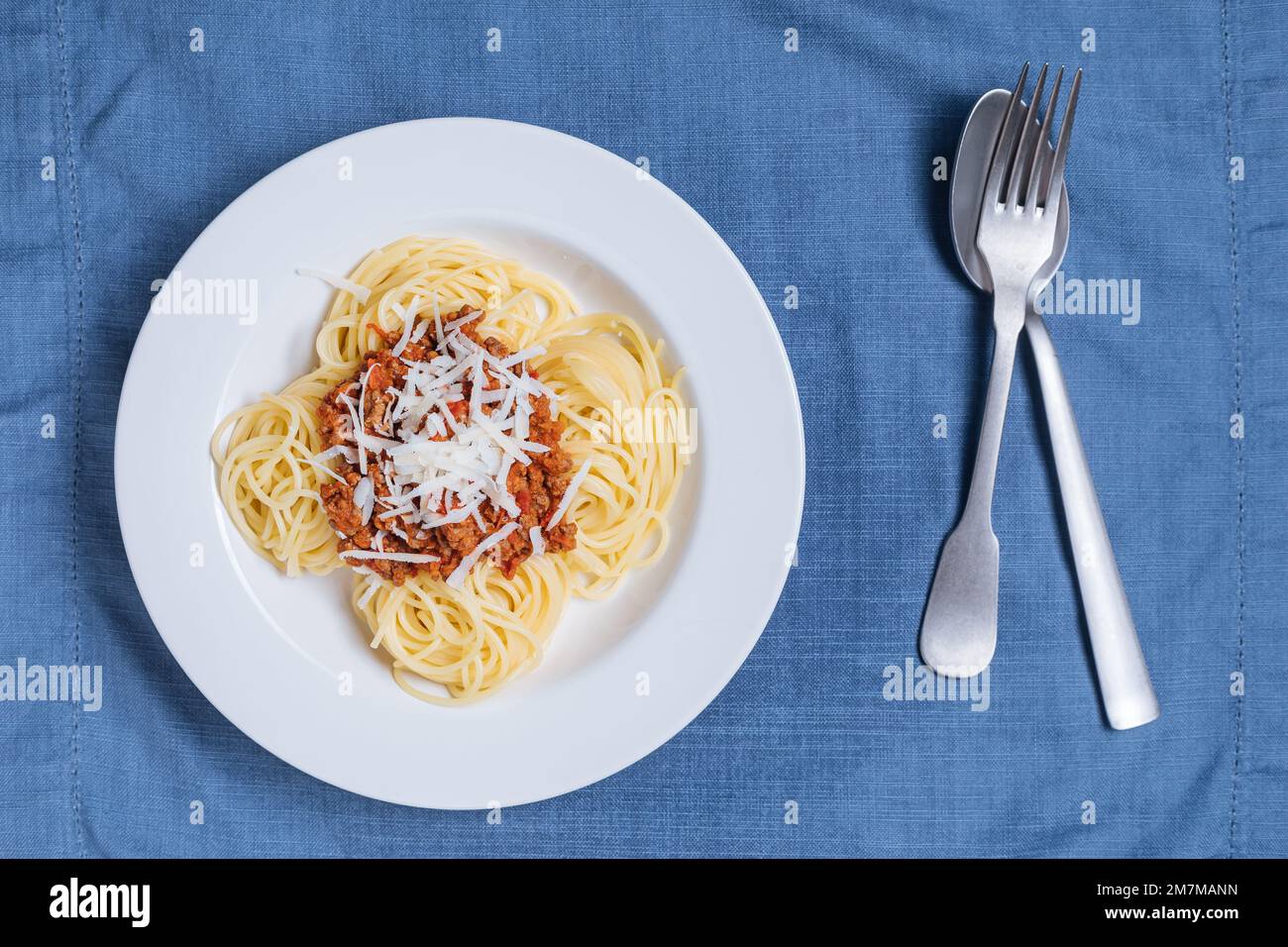 Spaghetti alla bolognese con parmigiano sul piatto bianco. Semplice sfondo blu e decorazione. Piatti tradizionali italiani, cucina mediterranea Foto Stock