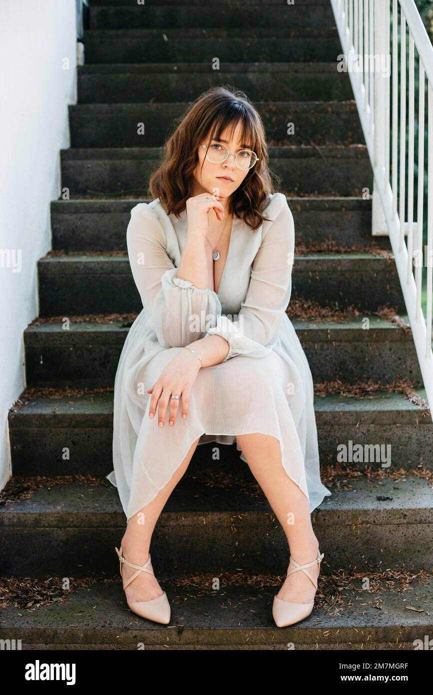 Giovane donna seduta sulle scale in abito estivo Foto Stock