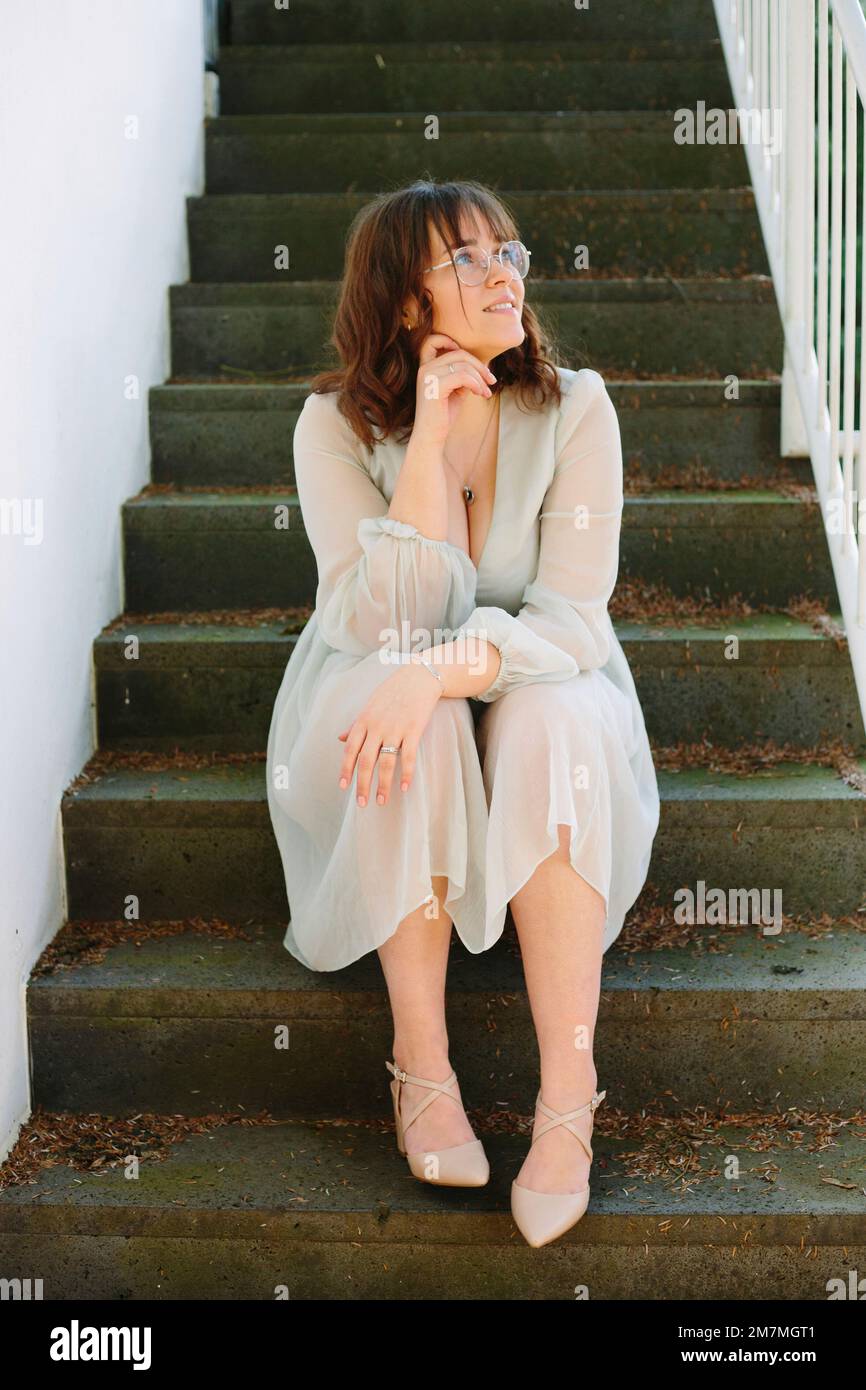 Giovane donna seduta sulle scale in abito estivo Foto Stock