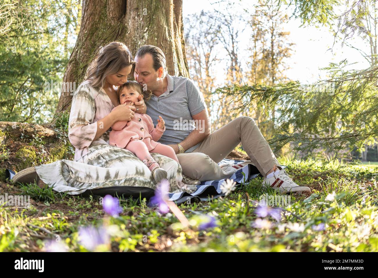 Europa, Germania, Baden-Wuerttemberg, Stoccarda, Castello di Hohenheim, felice famiglia seduta su coperta da picnic sotto l'albero Foto Stock