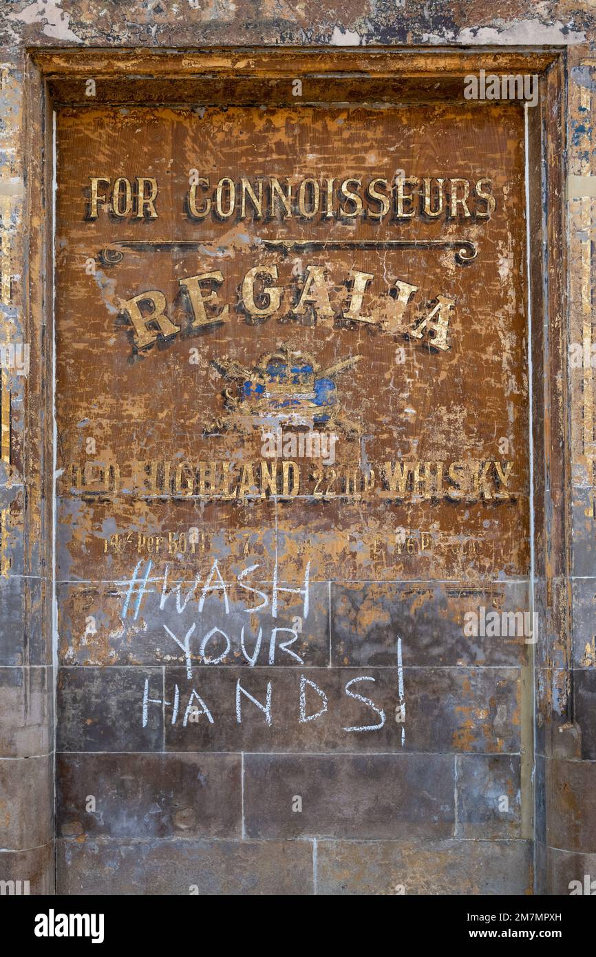 Regalia Highland Whisky vecchio segno con lavare le mani gessato in cima durante la pandemia di coronavirus, Partick, Scozia, Regno Unito Foto Stock