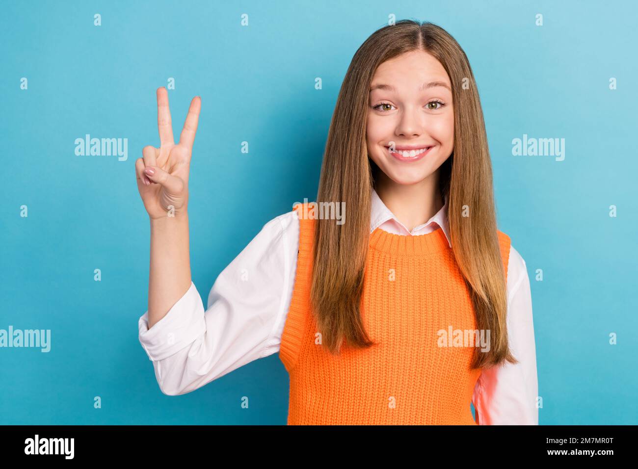 Ritratto foto di giovane allegro soddisfatto cute sorridente ragazza marrone capelli mostrando segno v indossare uniforme elegante isolato su sfondo di colore blu Foto Stock