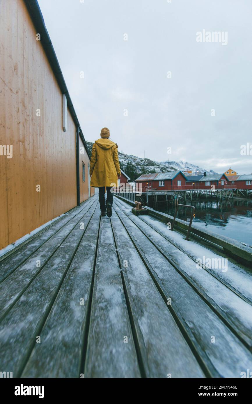 Giovane donna con impermeabile giallo in Norvegia, Lofoten, villaggio di pescatori Foto Stock