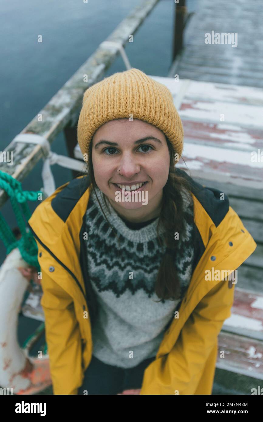 Giovane donna con impermeabile giallo in Norvegia, Lofoten, villaggio di pescatori Foto Stock