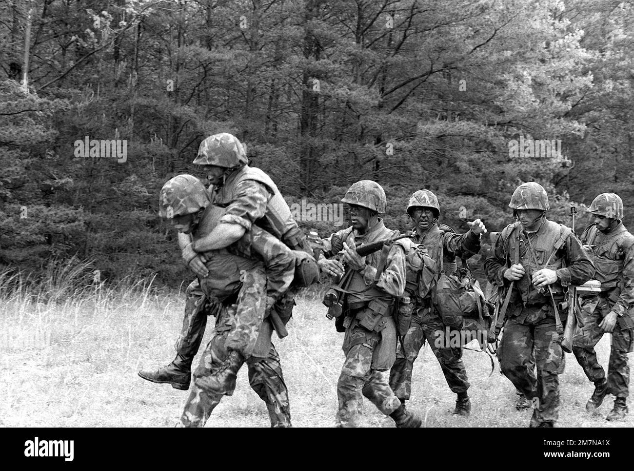 Una squadra di fucili marini si avvicina al traguardo dopo un percorso di resistenza di due miglia. Un membro della squadra sta portando un leader della squadra antincendio al traguardo. La corsa è stata parte dell'evento Combat Endurance and Survivability al Rifle Squad Combat Competition 1979. Base: Marine Corps base, Quantico Stato: Virginia (VA) Paese: Stati Uniti d'America (USA) Foto Stock