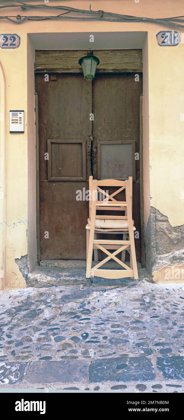 Due sedie di legno sono impilate davanti alla vecchia porta di Cefalù, in Sicilia Foto Stock