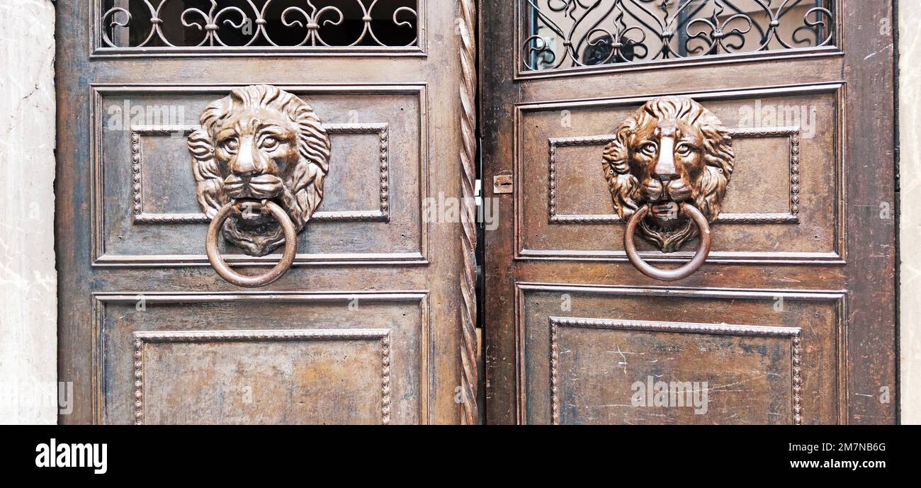 Porta frontale a doppia foglia con cornice in metallo e teste di leone come battitori nel villaggio di Cefalù, in Sicilia Foto Stock
