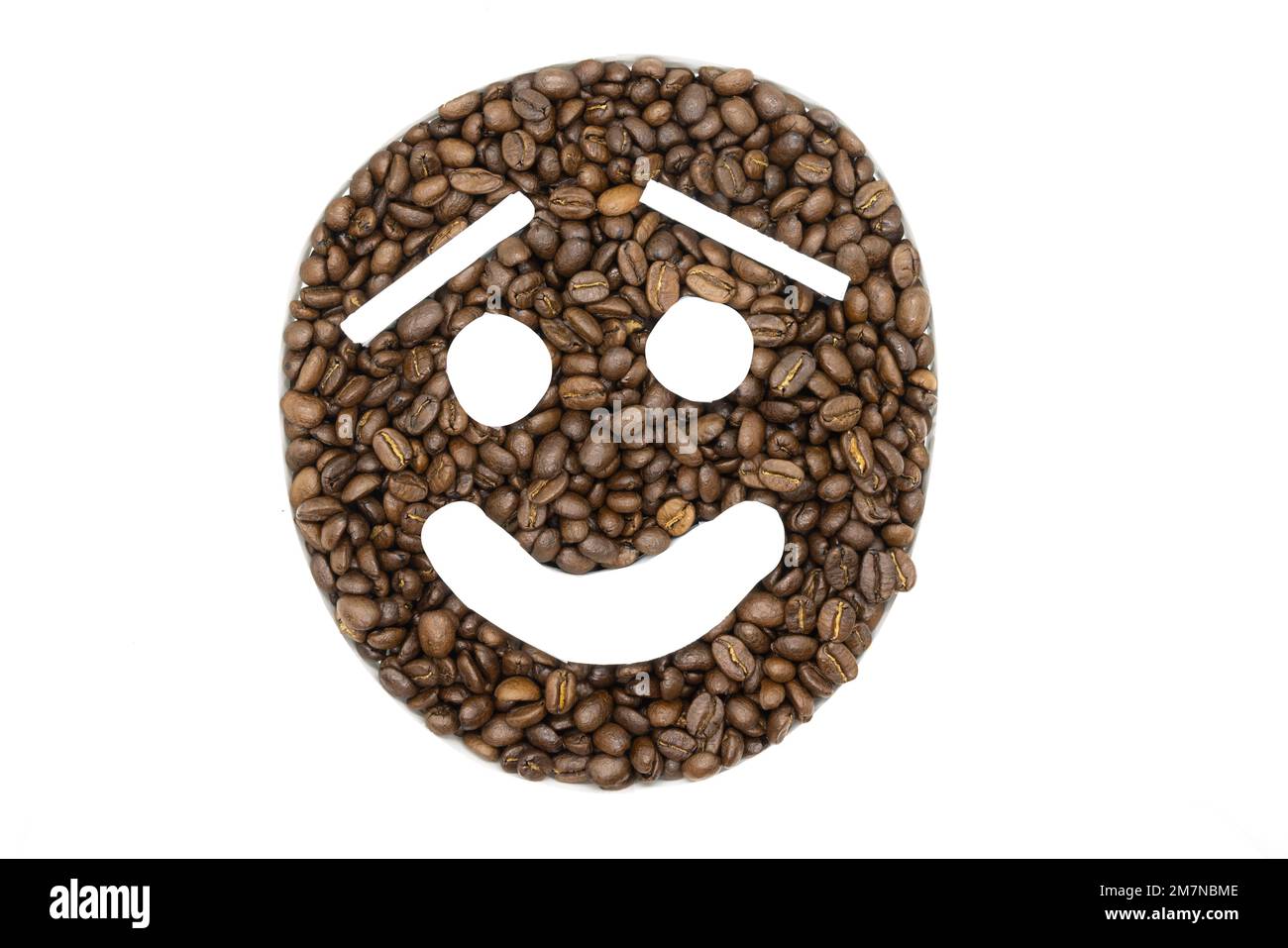 Chicchi di caffè disposti su uno sfondo bianco per apparire come un emoji Foto Stock