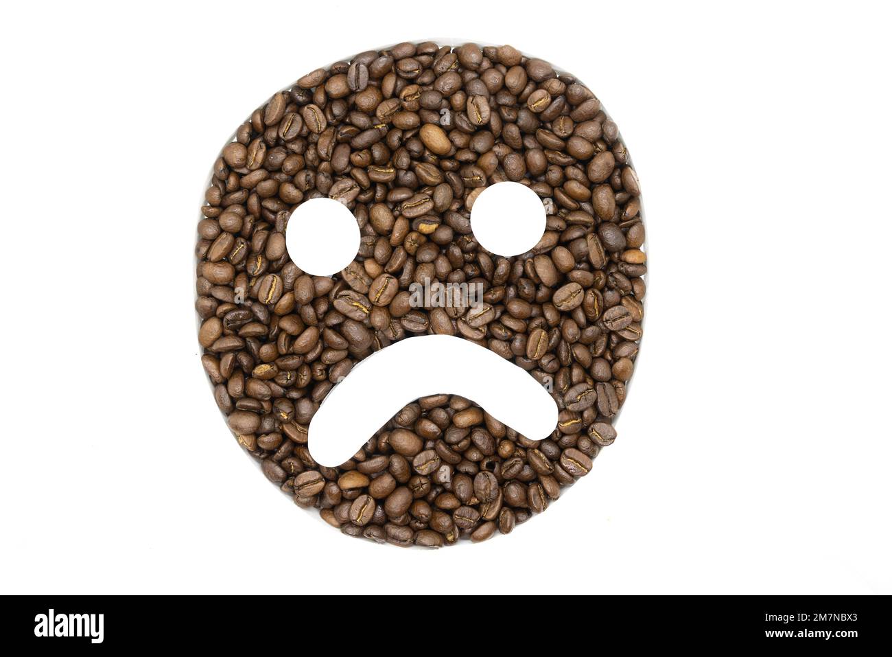 Chicchi di caffè disposti su uno sfondo bianco per apparire come un emoji Foto Stock