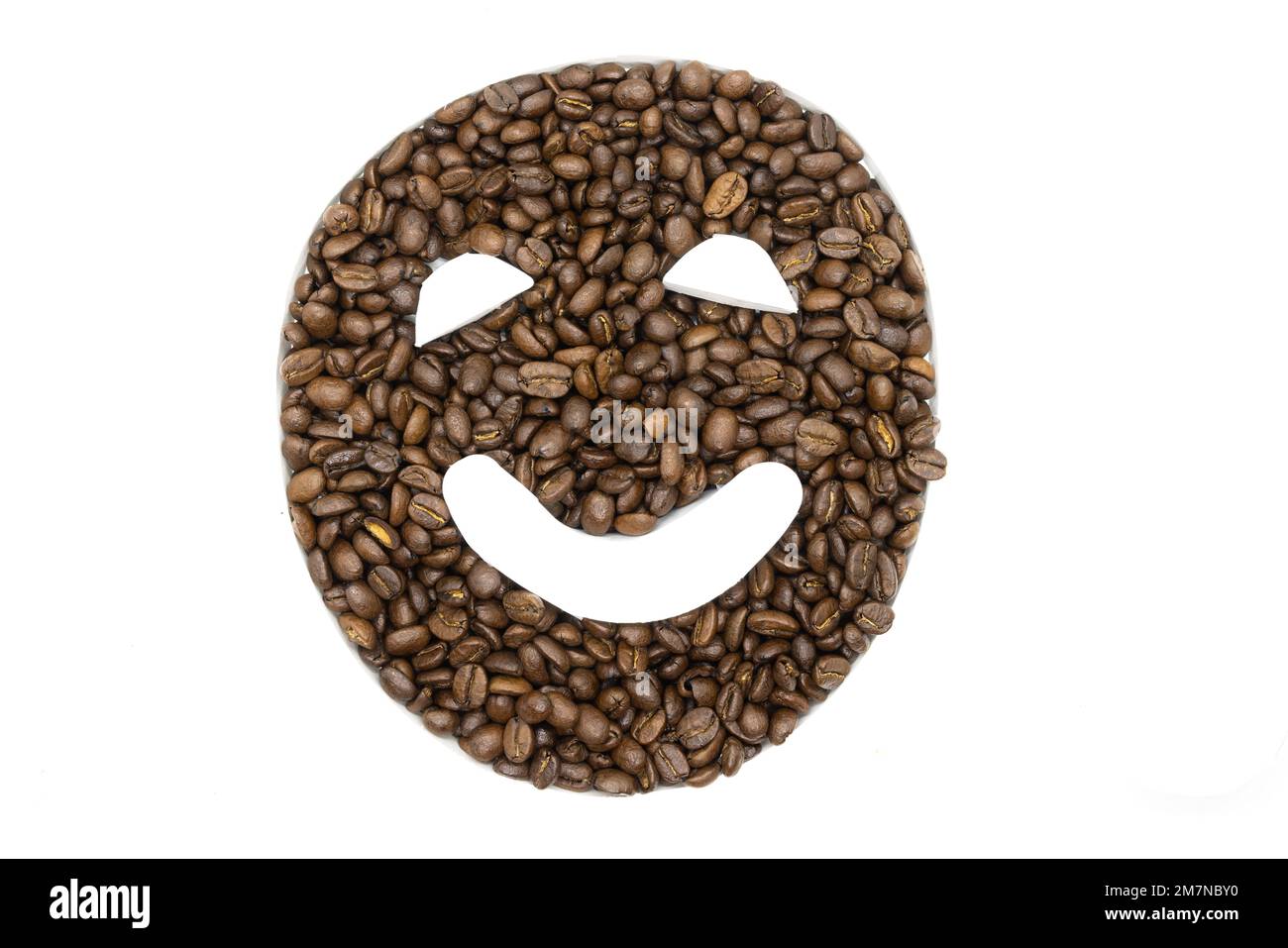 Chicchi di caffè disposti su uno sfondo bianco per apparire come un emoji Foto Stock