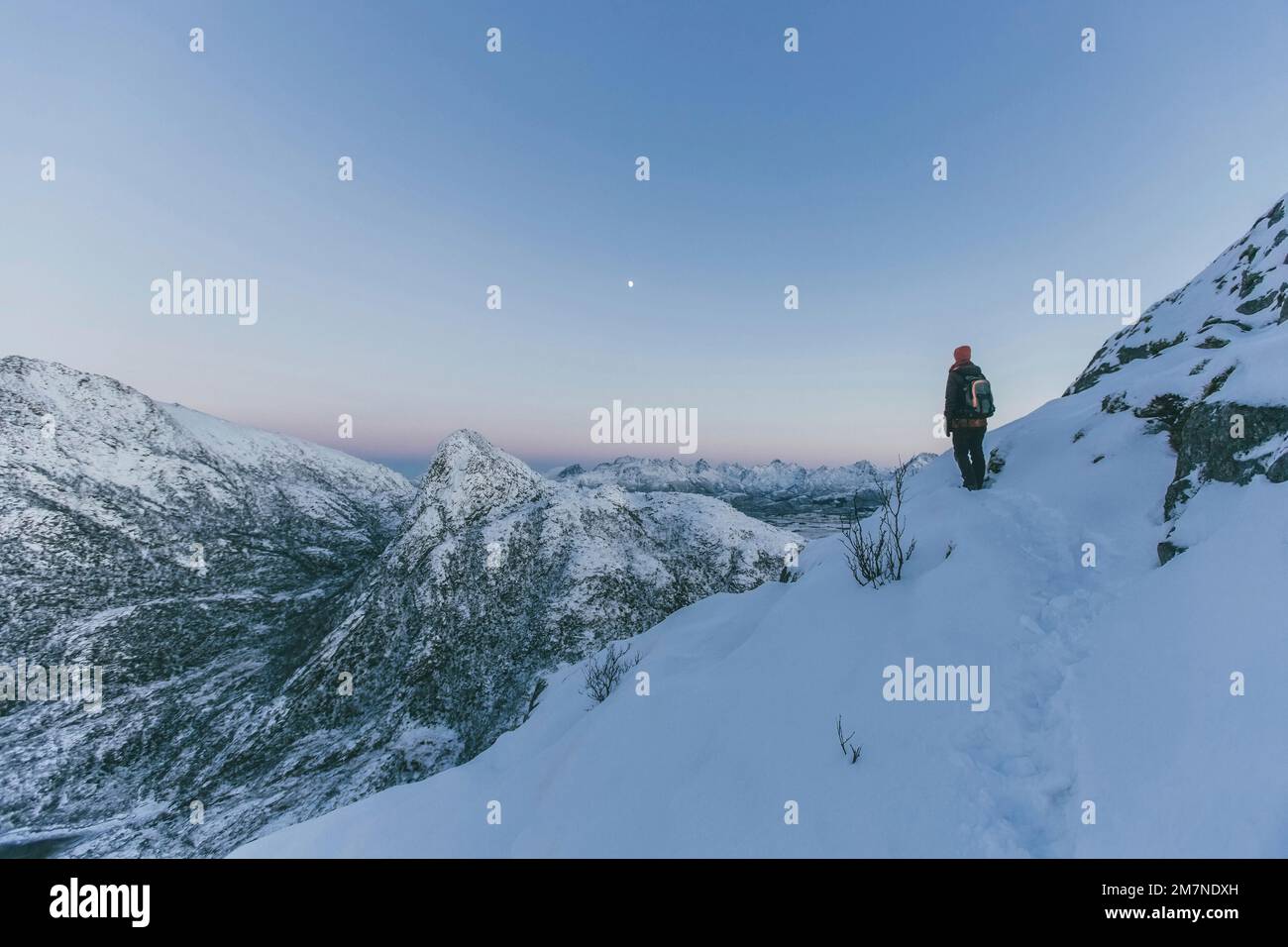 Giovane donna che si arrampica sulla neve dopo il tramonto a Vesteralen, Norvegia, arrivo a destinazione, montagna e la luna Foto Stock