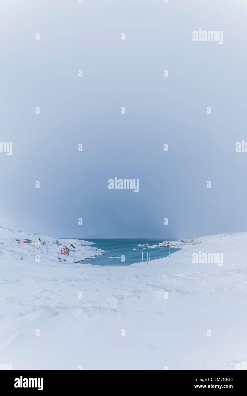 Innevato nel villaggio di pescatori sul fiordo in Norvegia, tipico paesaggio fiordo con neve, isolamento dal mondo esterno Foto Stock