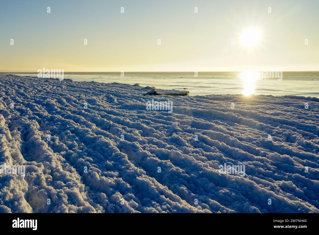 Bellissimo tramonto invernale sul Mar Baltico, le onde d'acqua si trasformano gradualmente in onde di ghiaccio a causa del forte gelo Foto Stock