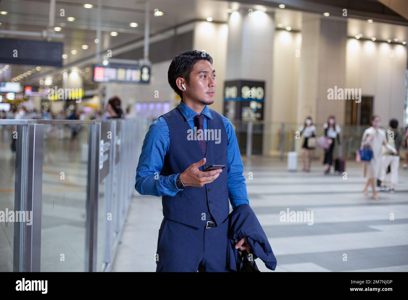 Un giovane uomo d'affari in città, in movimento, in un hub di trasporto, tenendo il telefono e guardando intorno. Foto Stock