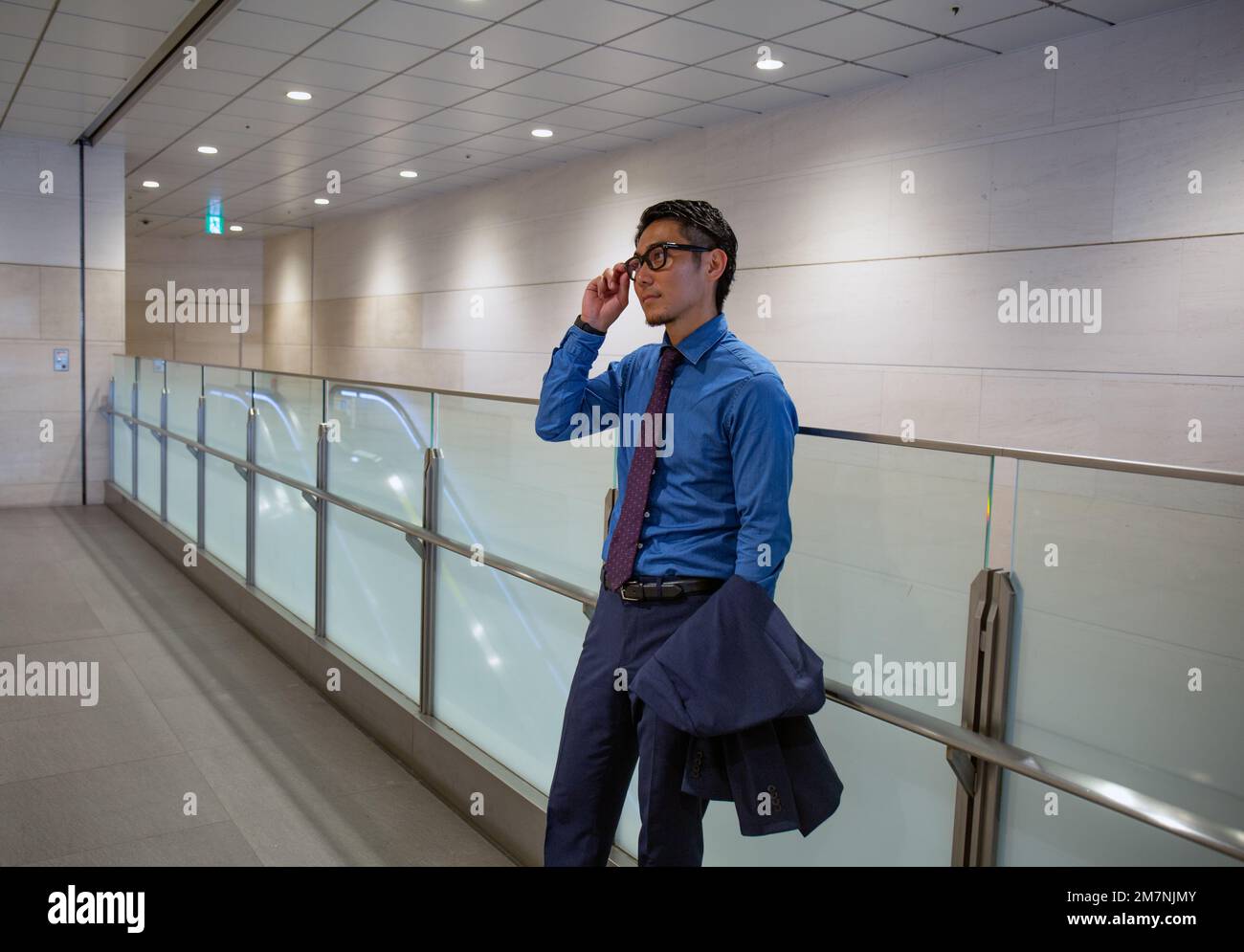 Un giovane uomo d'affari in città, in movimento, in un corridoio che parla sul suo cellulare. Foto Stock