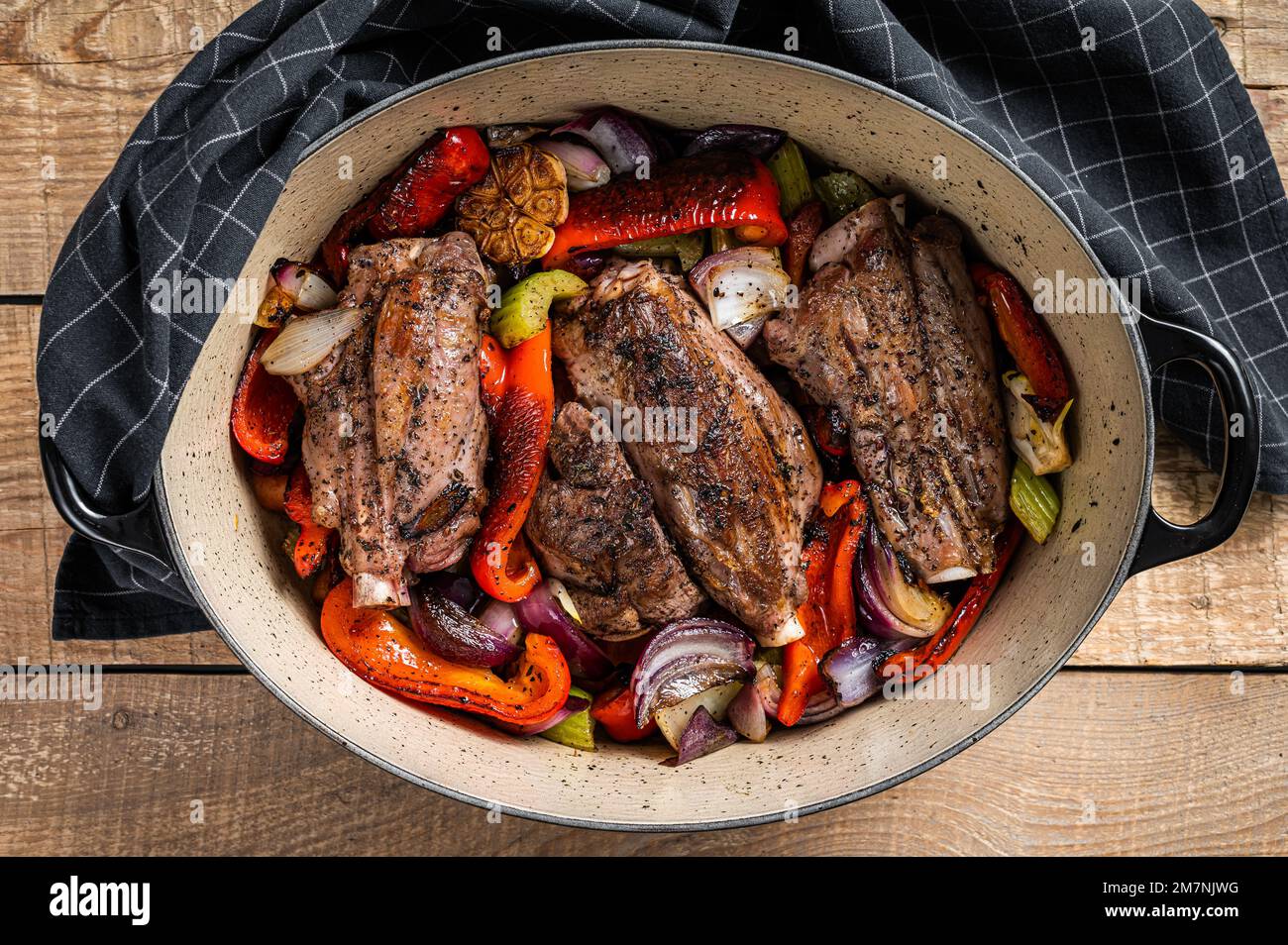 Stinco di agnello cotto a fuoco lento arrosto con verdure ed erbe aromatiche. Sfondo di legno. Vista dall'alto Foto Stock