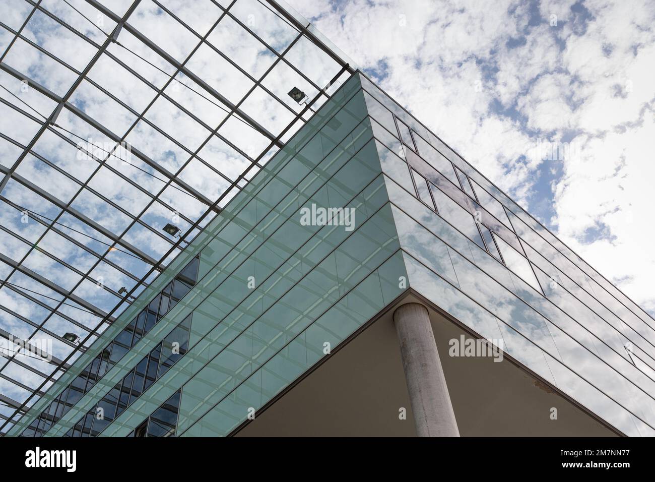 Il cielo blu e le nuvole bianche si riflettono nella facciata della casa e brillano attraverso il tetto di vetro. Foto Stock