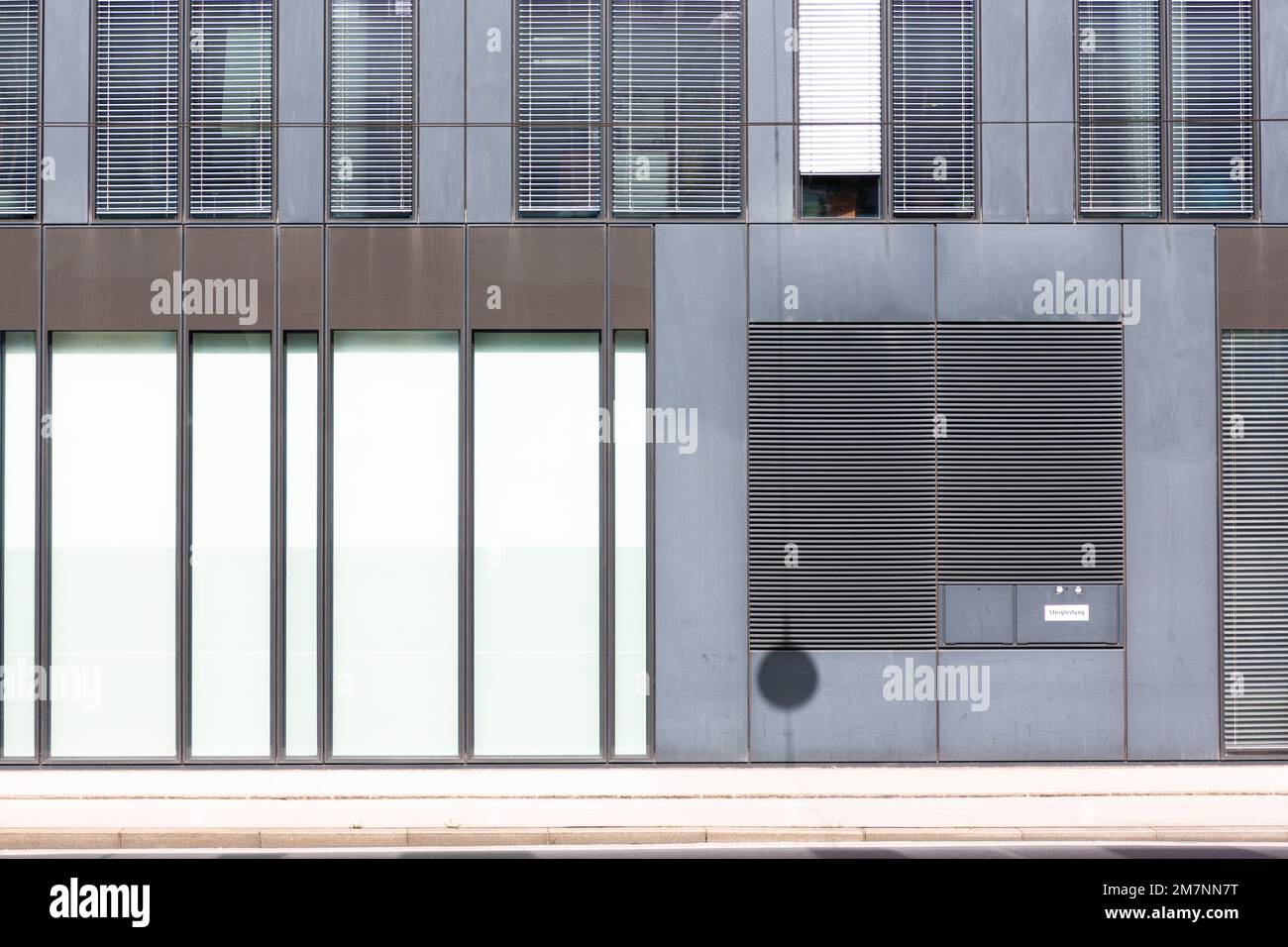 La disposizione delle persiane e degli elementi murali di un edificio forma un disegno grafico in bianco, marrone e grigio. Foto Stock