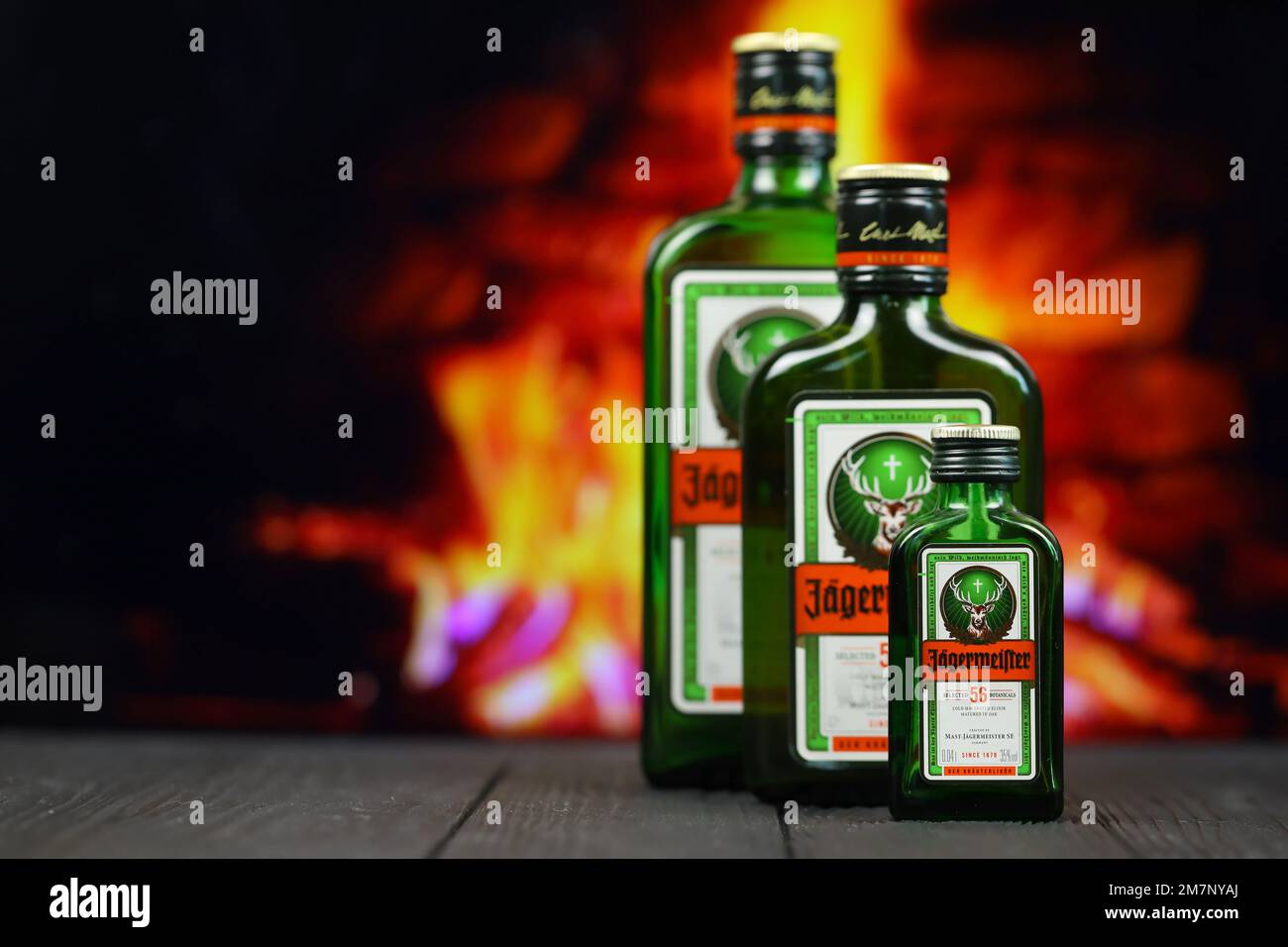 KIEV, UCRAINA - 4 MAGGIO 2022 Jagermeister bottiglia di alcol originale su tavolo di legno con camino rosso sullo sfondo. Produzione di alcool Elite Foto Stock