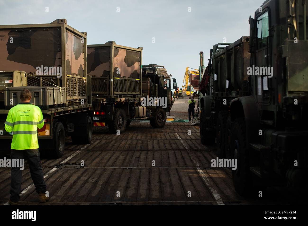 Un soldato dell'esercito australiano con il regiment 1st dell'ingegnere di combattimento, 1st Squadron del campo, carica un camion DI UOMO 40m, caricato con i sistemi di purificazione dell'acqua, vicino ad un rimontaggio medio del veicolo tattico, elemento di comando di logistica, forza rotazionale marina-Darwin (MRF-D) 22, Su una chiatta durante un movimento logistico combinato di attrezzature per esercizio Crocodile Response 22 a Darwin, NT, Australia, 12 maggio 2022. Il MRF-D 22 e l'esercito australiano sono stati caricati su chiatte civili per il trasporto, dimostrando la flessibilità di condurre l'assistenza umanitaria e il soccorso in caso di calamità all'interno di diversi operati Foto Stock