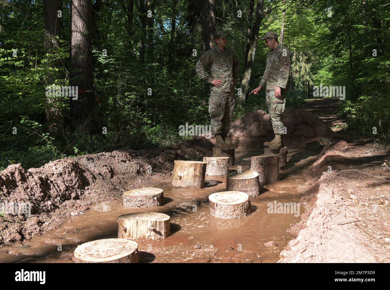 Airman Ruben Kuehn (a sinistra), e Airman 1st Classe Dylan Galvan (a destra), 786th ingegnere civile Squadron apprendisti di manutenzione impianti di acqua e carburante, discutere la configurazione del log per il leggendario 2nd annuale fango Run presso la base aerea di Ramstein, Germania, 11 maggio 2022. I tronchi forniscono ai corridori un ostacolo da superare mentre completano il leggendario Mud Run annuale 2nd. Foto Stock