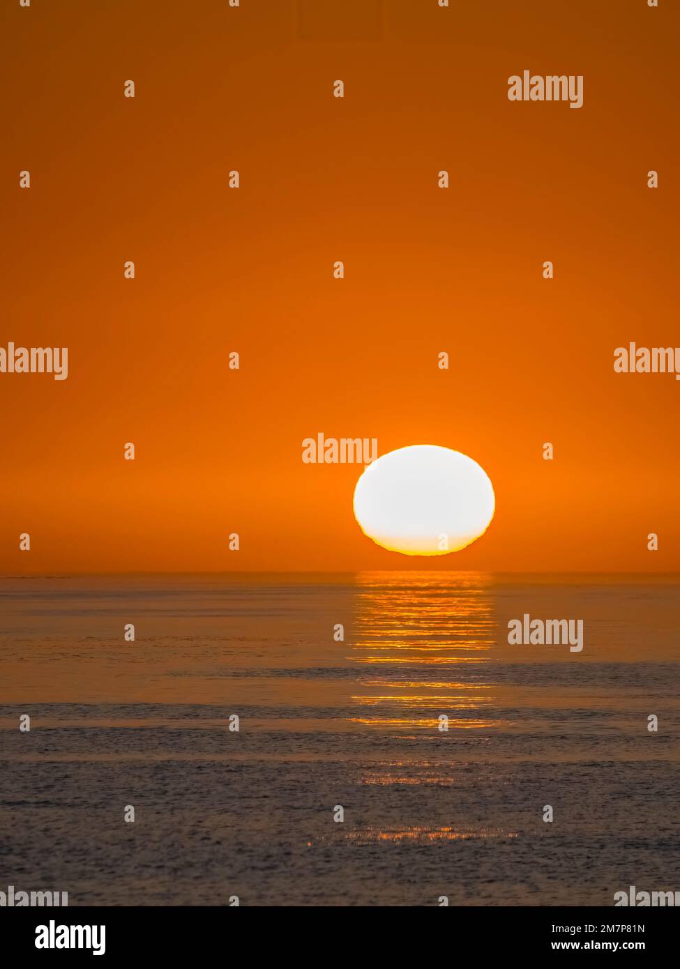 Il sole sta per passare in un cielo arancione vuoto appena sopra l'orizzonte sul Golfo del Messico Foto Stock