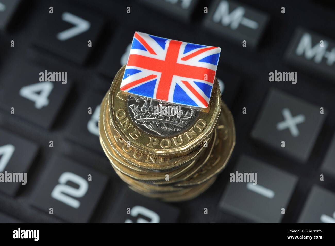 MONETE BRITANNICHE DA UNA LIBBRA CON LA BANDIERA DELL'UNIONE SUL CALCOLATORE RE COSTO DELLA CRISI VIVENTE L'INFLAZIONE DI ECONOMIA ECC UK Foto Stock