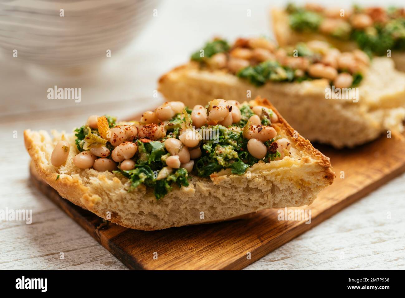 Pesto di kale vegano fatto in casa con bruschetta di fagioli bianchi su un tagliere. Foto Stock