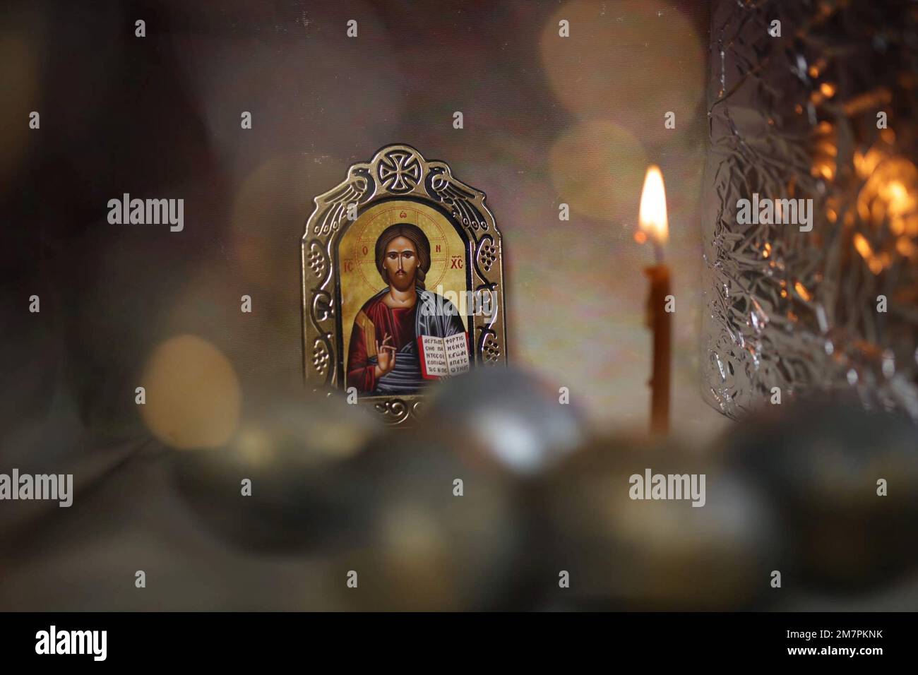 Icona di Cristo, uova di pasqua soffocate e candela sullo sfondo di una chiesa cristiana ortodossa. Fiamma di candela nel buio sacro interno della chiesa Foto Stock