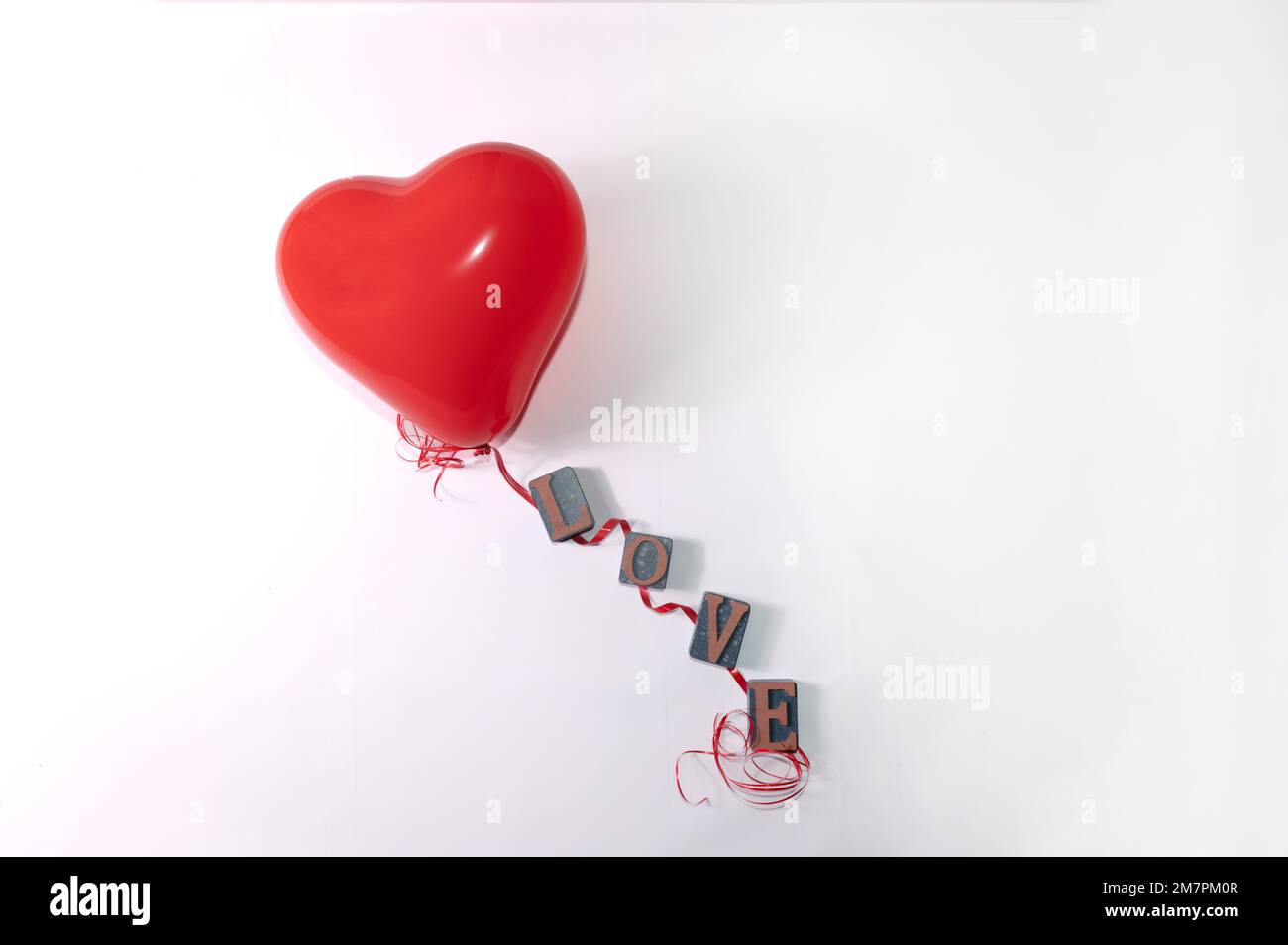 Palloncino a forma di cuore rosso e cordicella rossa con lettere per la parola amore su sfondo bianco Foto Stock