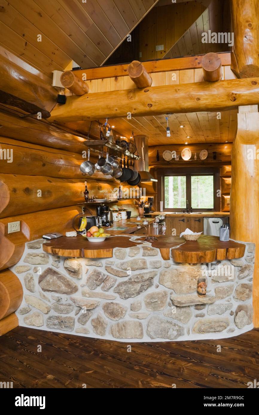 Cucina con barra ricurva costruita con pietre di campo e rocce porose all'interno di una casa in legno scandinavo di cedro rosso artigianale. Foto Stock