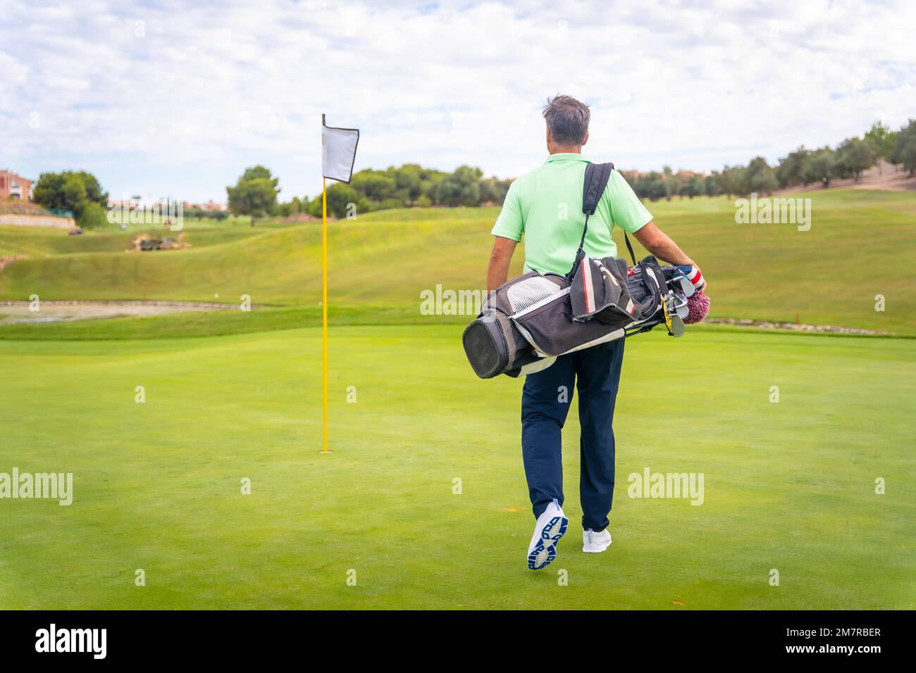 Ritratto del golfer maschio che cammina giù le borse di trasporto del fairway, giocare il golf Foto Stock