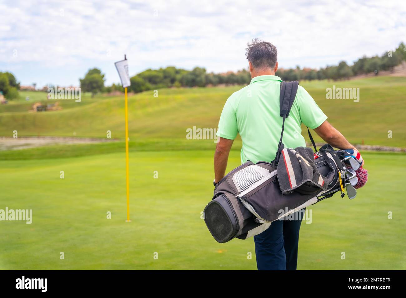 Ritratto del golfer maschio che cammina giù le borse di trasporto del fairway, giocare il golf Foto Stock