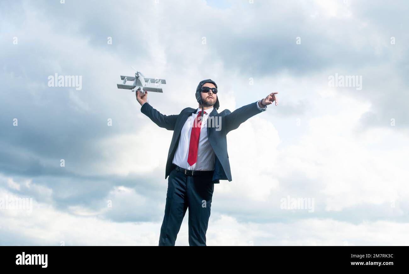 uomo d'affari di successo in tuta e cappello pilota lancio aereo giocattolo su sfondo cielo Foto Stock